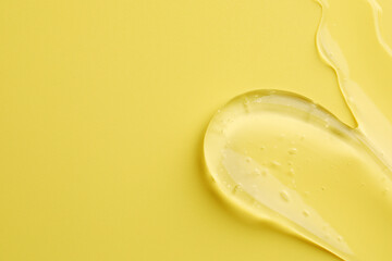 Sample of clear cosmetic gel on yellow background, top view. Space for text