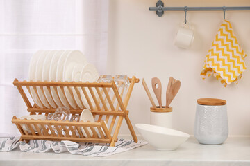 Drying rack with clean dishes on countertop in kitchen