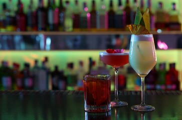 Different fresh alcoholic cocktails on counter in bar. Space for text