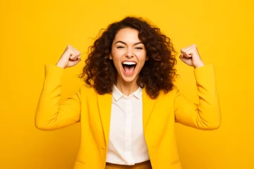 Fotobehang Woman with curly hair and yellow jacket is holding her arms up. © valentyn640