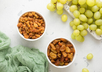 Sweet dried green raisins with ripe raw grapes on light background.Top view.