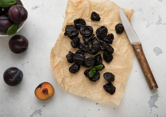 Dried sweet prunes with plums and kitchen knife on light bacground.Top view.