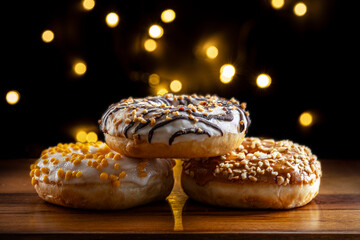 assorted glazed donuts on wooden surface and festive bokeh backgrond