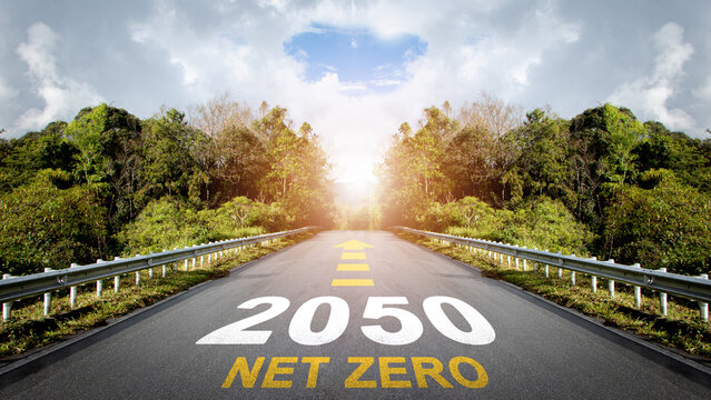 Net zero by 2050. Text Net Zero 2050 with arrow symbol written on the road in the middle of asphalt road with at sunset.Net zero greenhouse gas emissions target. Climate neutral long term strategy.