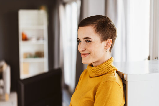 Joyful Young Woman in Yellow Sweater, Short Hair, Smiling in Contemporary Living Room