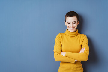 Laughing Young Woman in Yellow Sweater, Short Hair, with Copyspace, Standing in Front of Blue Wall