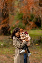 Young woman holding cute baby girl in the autumn park