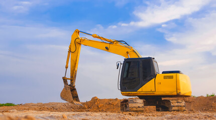 Yellow excavator is leveling the ground for construction area of industrial building in...