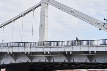 Man riding on bicycle across the bridge in the city.