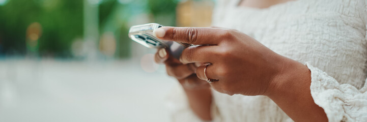 Closeup of young woman holds a smartphone in her hands and scrolls through the news feed. Close-up...