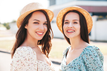 Two young beautiful smiling hipster female in trendy summer dresses  clothes. Sexy carefree women posing in the street. Positive models having fun at sunny day. Going crazy