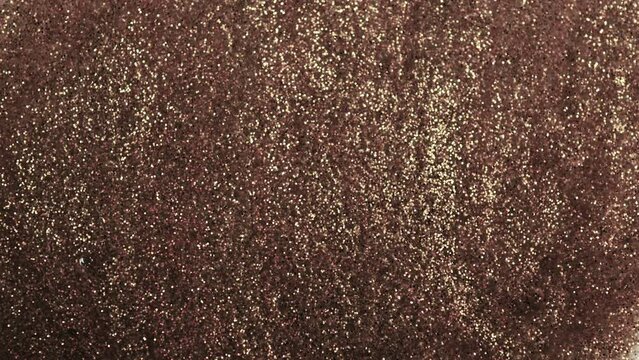 Antique gold. Grunge background molten gold, bronze, copper. Macro video glitter fluid motion. Golden glitters. Yellow shiny background.  Black glitters mixed with gold glitters.