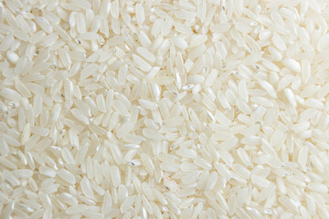 Dry Uncooked White Rice Background - Top View, Flat Lay. Scattered Raw Long Grain Rice. Asian Cuisine and Culture. Healthy Eating Ingredients. Diet Food