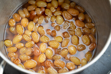 Grapes boiling in a pot with sugar, as part of the process of making homemade jam