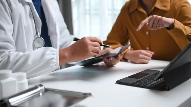 A professional physician talks to discuss results or symptoms and gives a recommendation to a male patient and signs a medical paper .
