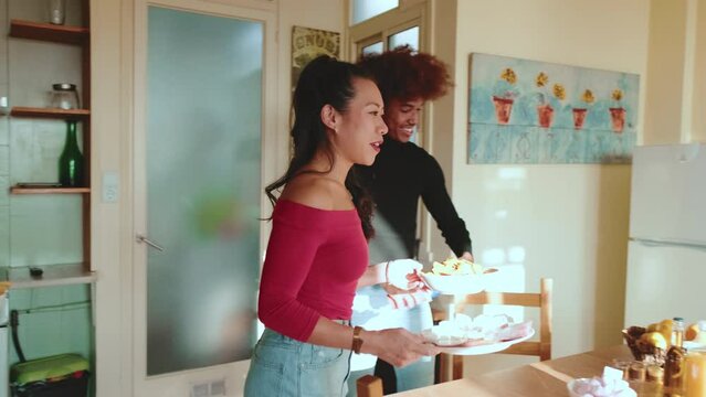 Friends arranging plates of snacks while having fun chatting at house party