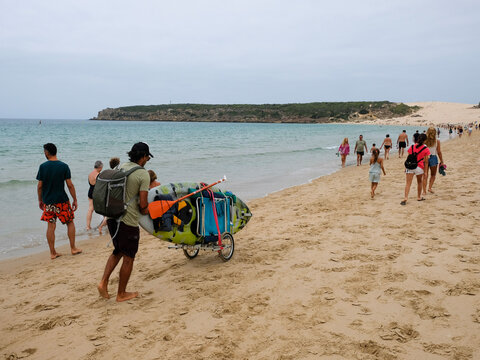 Playa de Valdevaqueros, C&aacute;diz, personas caminando sobre la arena, surfero transportando su tabla