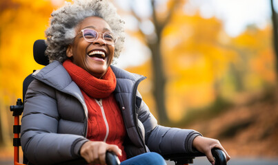 Joyful elderly African American woman with gray hair enjoying the autumnal park from her wheelchair, showcasing independence and positivity