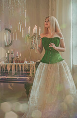 Atmosphere Vintage style Lady in medieval corset and fancy evening dress, candles around, magic in...
