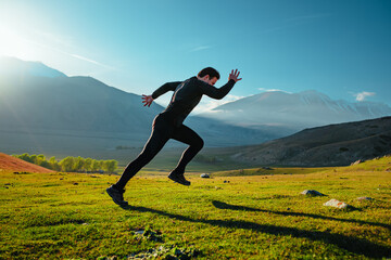 Athletic young man running on mountains background at sunny day