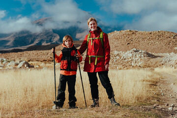 Happy young woman tourist with son on mountains background at autumn
