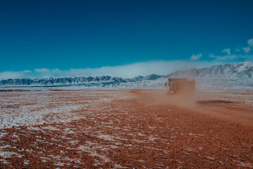 Truck driving on dusty road in the mountains in winter