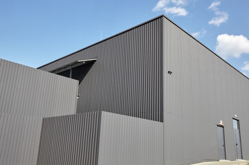 Corrugated steel warehouse or factory industrial building against blue sky. Architecture. Metal...