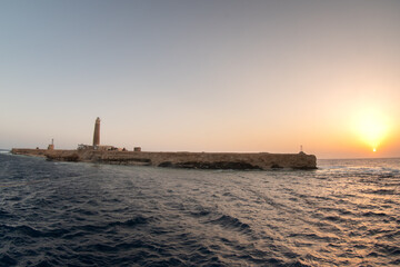 The lighthouse on the Big Brother Island during sunset, sea view against the sun, Red Sea, Egypt