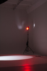 A red spotlight in a photo studio leaves a round spot of light on the floor