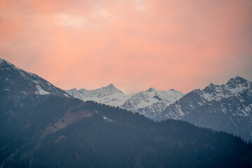 red orange dusk dawn colors over snow covered himalaya mountains and fluffy clouds showing hill stations in jhibbi kullu manali - obrazy, fototapety, plakaty
