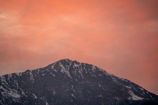red orange dusk dawn colors over snow covered himalaya mountains and fluffy clouds showing hill stations in jhibbi kullu manali