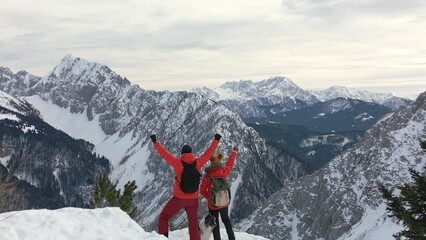 Hikers rejoice in reaching the summit of the peak with their canine companion, drone video