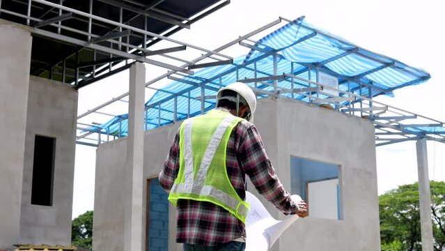 Middle-aged architect, foreman reading bluprint project paperwork standting against blue sky, engineering, small business Indian contractor male inspect unfinished real estate project workplace