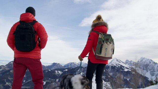 Mountaineers take photo of snowy landscape in the mountains with their dog in winter