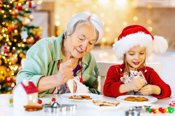 An elderly woman and a child are decorated with icing ginger cookies on Christmas eve.