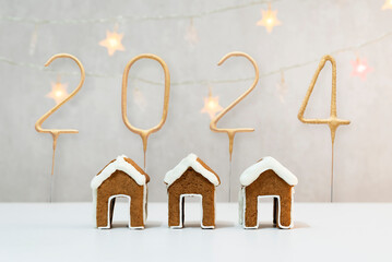 Three little gingerbread houses for teacup and golden number 2024, garland on background. Christmas...