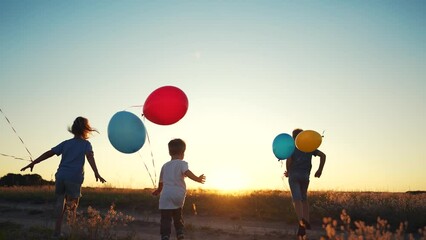 children run across the field. happy family kid dream concept. a group of children are run along road field with colorful balloons. guys run across field with large colored lifestyle balloons