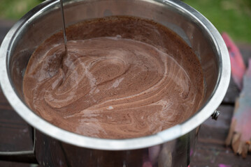 Melted chocolate in a stainless steel bowl, outdoors