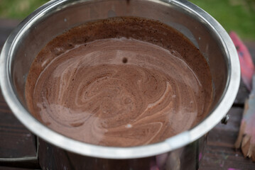 Melted chocolate in a stainless steel bowl, outdoors
