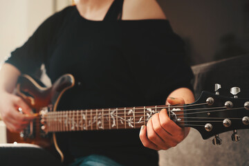 Woman plays chord on electric hollowbody guitar with richly ornamented ftretboard. Black naked...