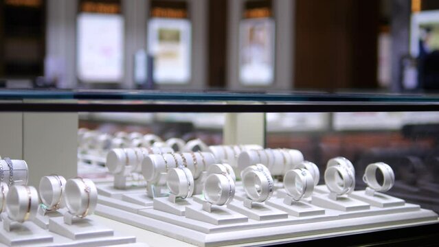 Store window displays jewelry bracelets made of different metals. Fine jewelry attracts with its beauty, demonstrating skill of jewelers. Wide range allows everyone to choose jewelry to their liking.