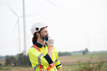Male engineer using radio communication at windmill field farm. Male engineer working at at wind...