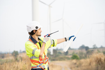 Male engineer using radio communication at windmill field farm. Male engineer working at at wind...