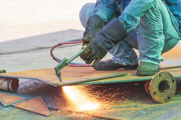 Close up of welder hand is cutting iron plate with acetylene gas welding torch machine in...