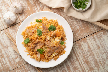 Stir fried instant noodles with BBQ pork sauce in white plate.top view