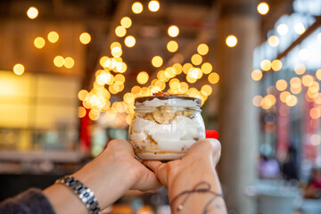 Woman holding banana dessert with bokeh effect lights in the background