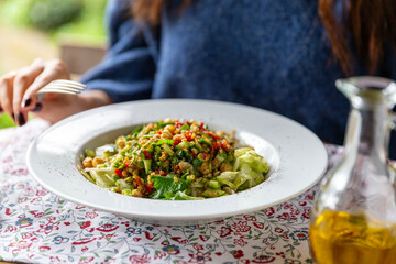 Woman in blue sweater eating healthy salad served with olive oil