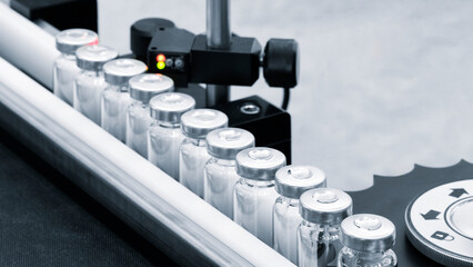 Vaccine production in a pharmaceutical factory, conveyor with the glass jars, modern pharmaceutical...