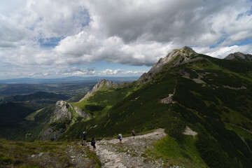 Fototapeta na wymiar Polish Tatras, people go hiking to Mount Giewont, summer tar sky with clouds.