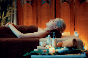 Aromatherapy massage ambiance or spa salon composition setup with focus decor candles and spa accessories on blurred woman enjoying blissful aroma spa massage in resort or hotel background. Quiescent